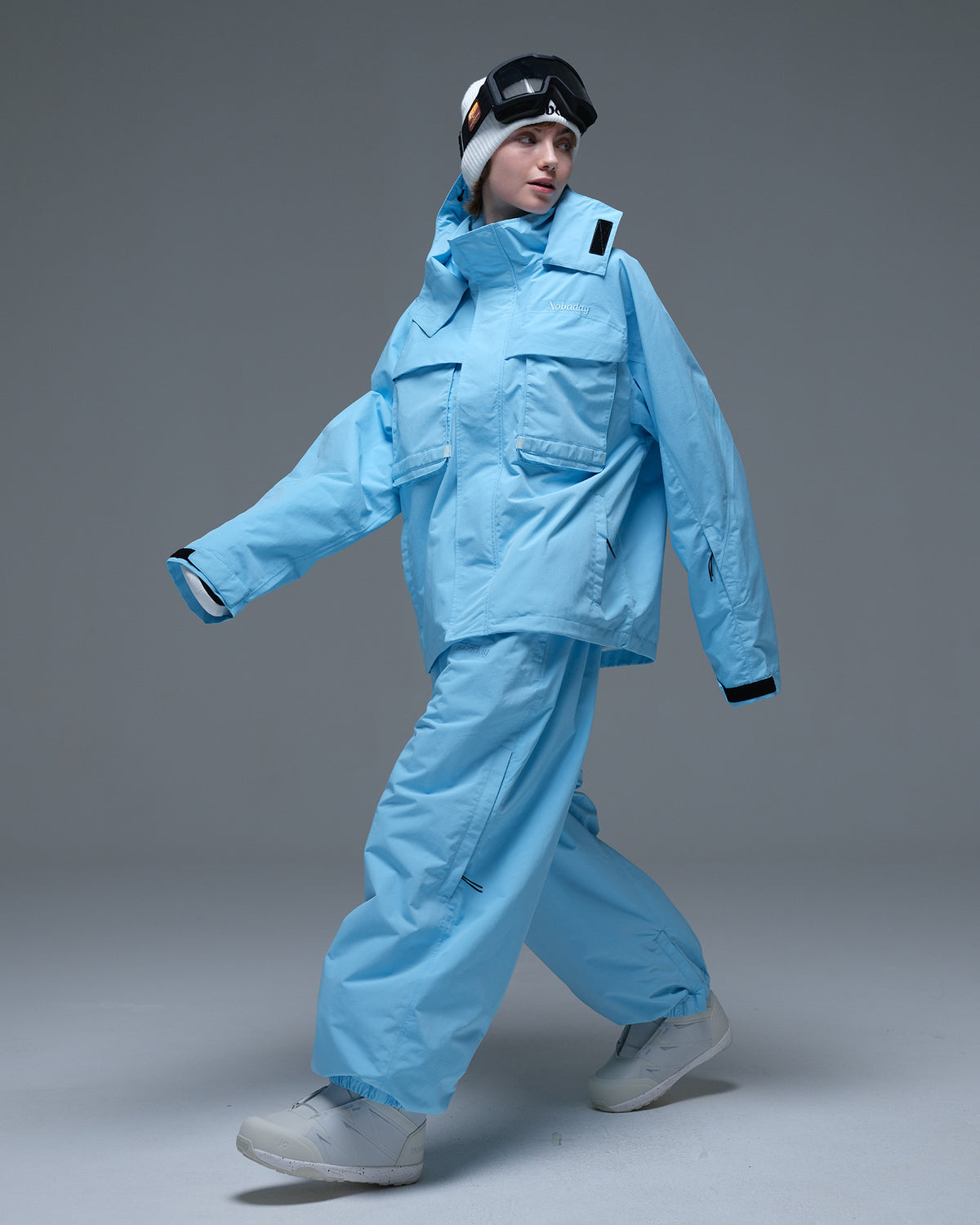 Full-body action view of a model wearing the sky blue Nobaday Women’s Pure Free Drift Snow Jacket with matching snow pants