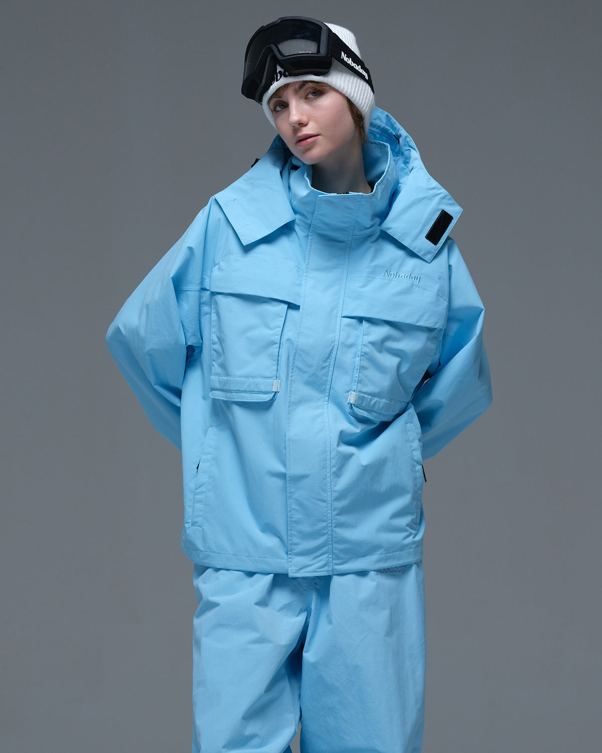 Half-body view of a model wearing the sky blue Nobaday Women’s Pure Free Drift Snow Jacket with large front utility pockets