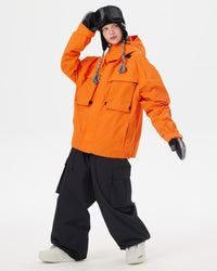 Full-body pose of a woman wearing the NOBADAY Women's Pure Free Freestyle orange snow jacket with black cargo snow pants