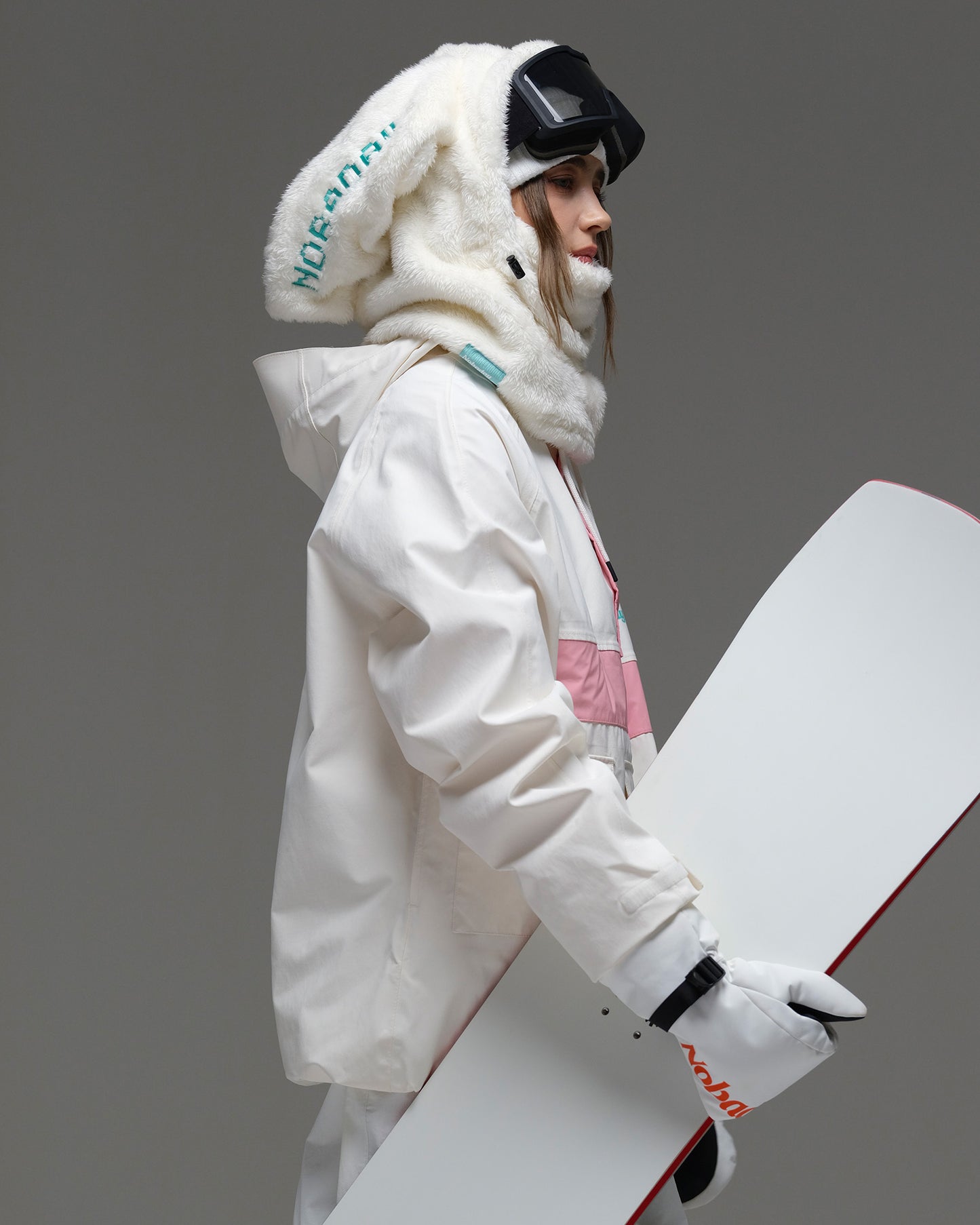 Side view of the ivory and pink Nobaday Women’s Juicy Candy Retro Snow Jacket styled with snowboard gear
